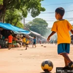 Home 23 캄보디아 축구 국가대표 - A vibrant street football scene in Phnom Penh, Cambodia, showing enthusiastic children wearing color...